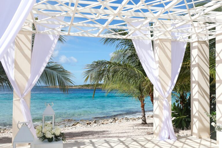 White beach cabana with curtains overlooking a turquoise sea