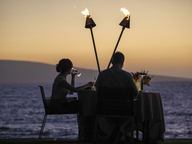Couple at a table for two by the sea at sunset