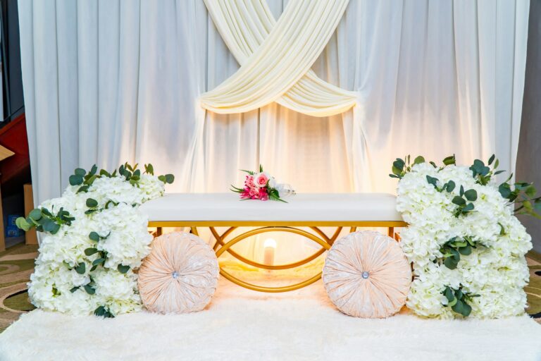 White draped backdrop with a seat for two and white flowers