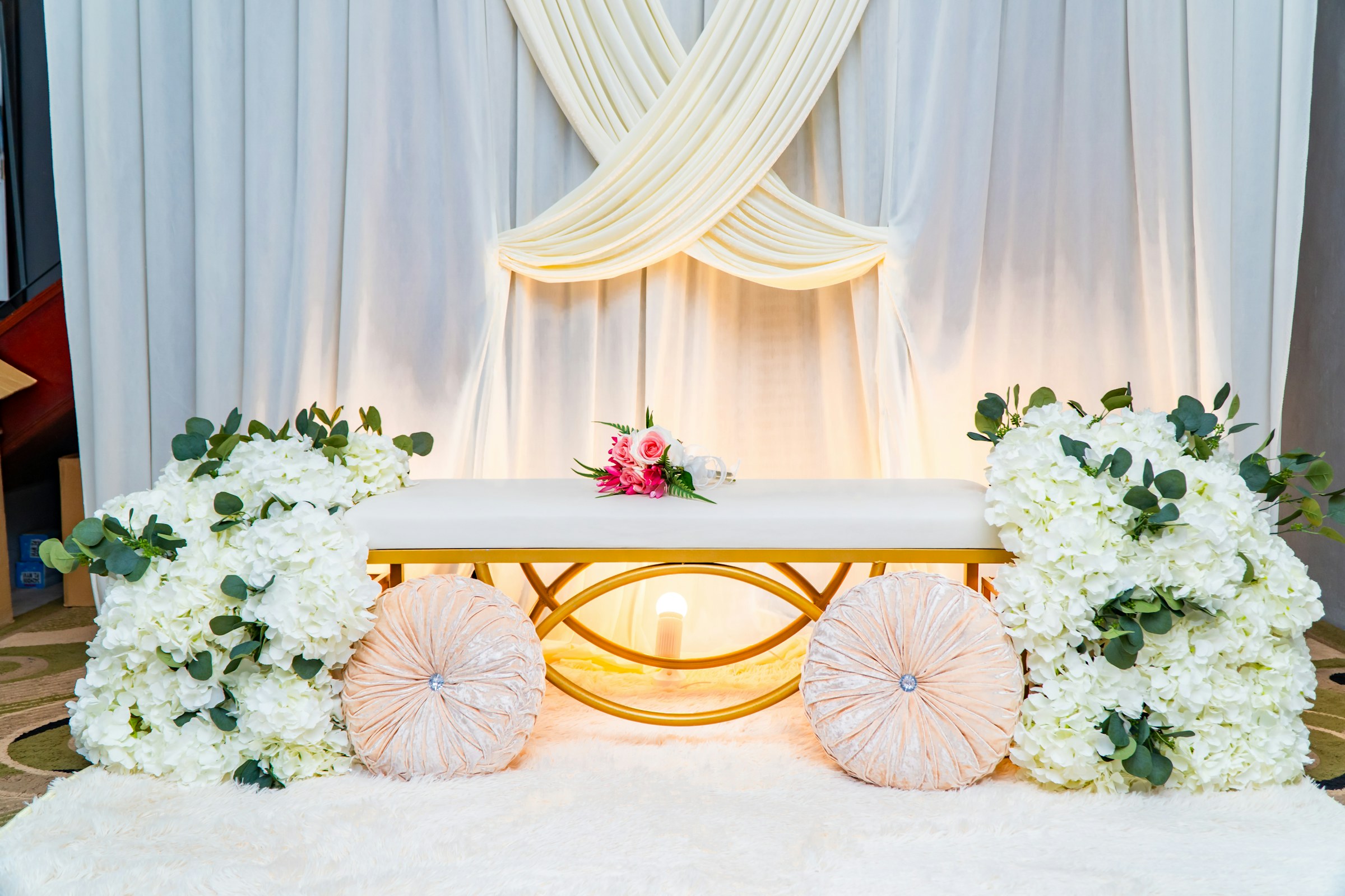 White draped backdrop with a seat for two and white flowers